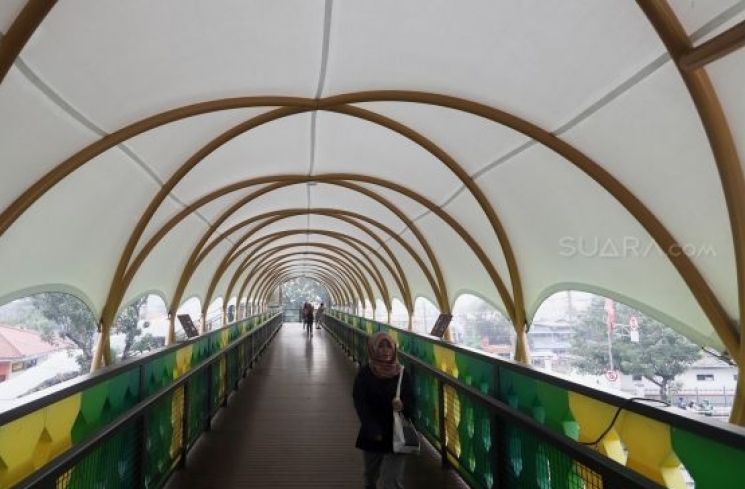 Pejalan kaki melintas di jembatan penyeberangan orang (JPO) Pasar Minggu, Jakarta, Rabu (22/1).[Suara.com/Angga Budhiyanto]